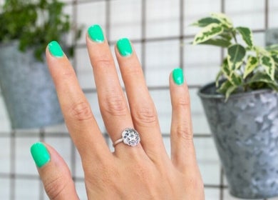 Close-up of a hand with emerald green nails at Wild Beauty, London, England, GB with potted plants in background.
