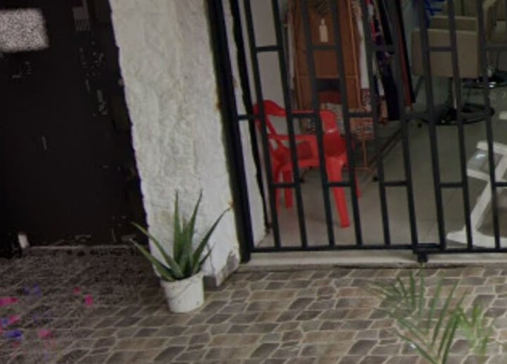 Entrada de Garnet Florida Nueva en Medellín, Antioquia, CO con sillas rojas y plantas decorativas.