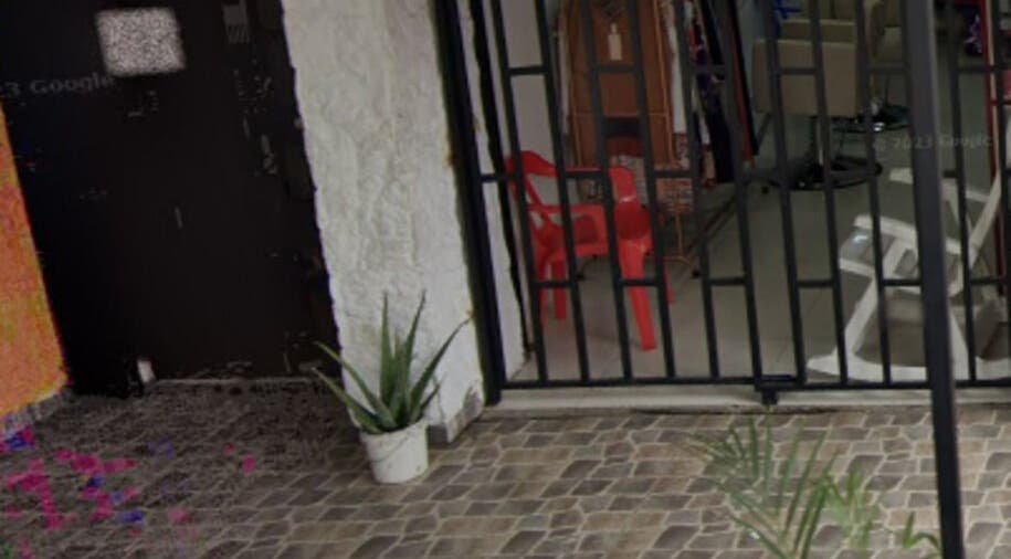 Entrada de Garnet Florida Nueva en Medellín, Antioquia, CO con sillas rojas y plantas decorativas.