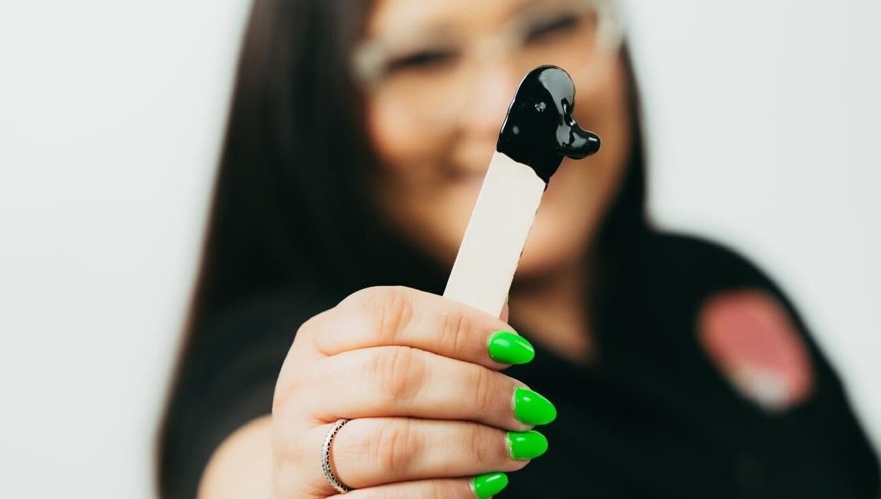 Mujer sosteniendo espátula con cera negra en The Waxing Room, Mayaguez, Puerto Rico, US.