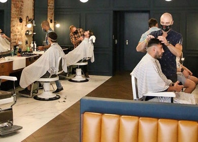 Interior of Hermanos Barbershop Loop Street in Cape Town, showcasing skilled barbers and elegant decor.