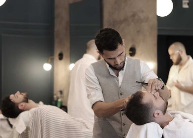 Hermanos Barbershop Loop Street stylist trimming a client's beard in Cape Town, Western Cape, ZA.