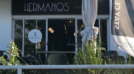 Entrance of Hermanos Barbershop Green Point, Cape Town, Western Cape, ZA, showcasing modern design and greenery.