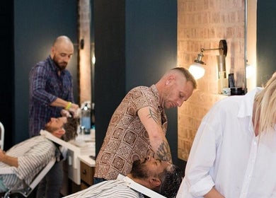 Stylish interior of Hermanos Barbershop Green Point in Cape Town, showing barbers at work.