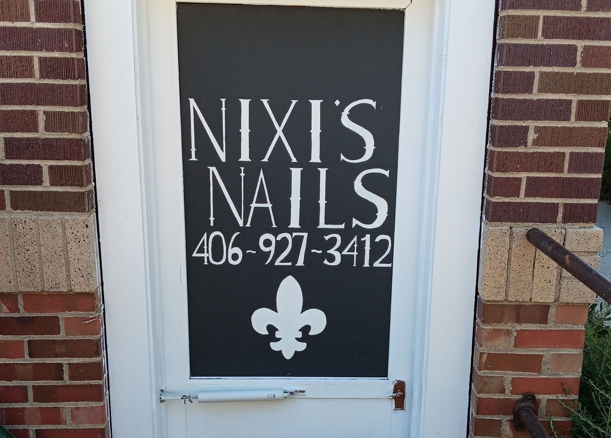 Front door of Nixi's Nails Salon in Roundup, Montana, US with stylish signage.