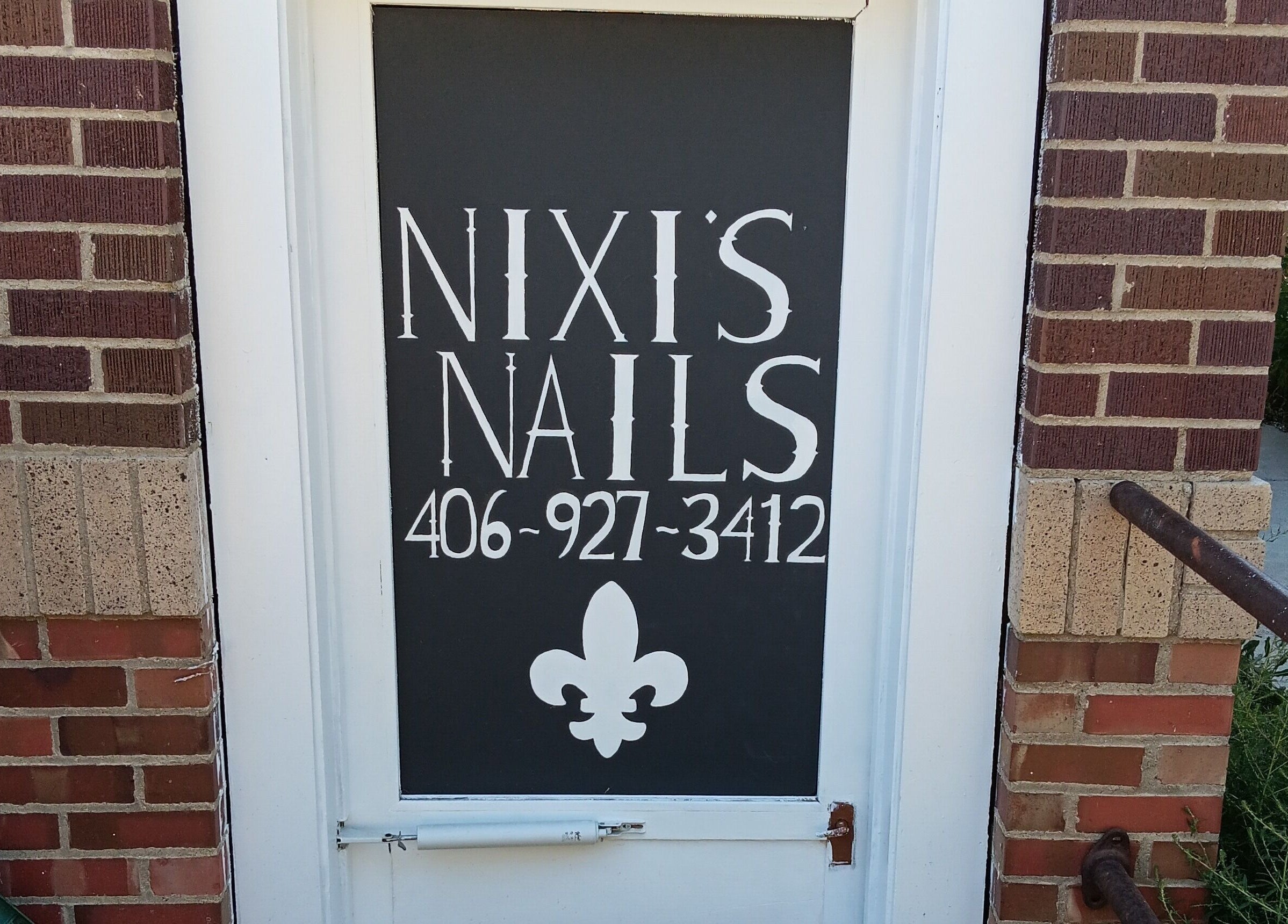 Front door of Nixi's Nails Salon in Roundup, Montana, US with stylish signage.