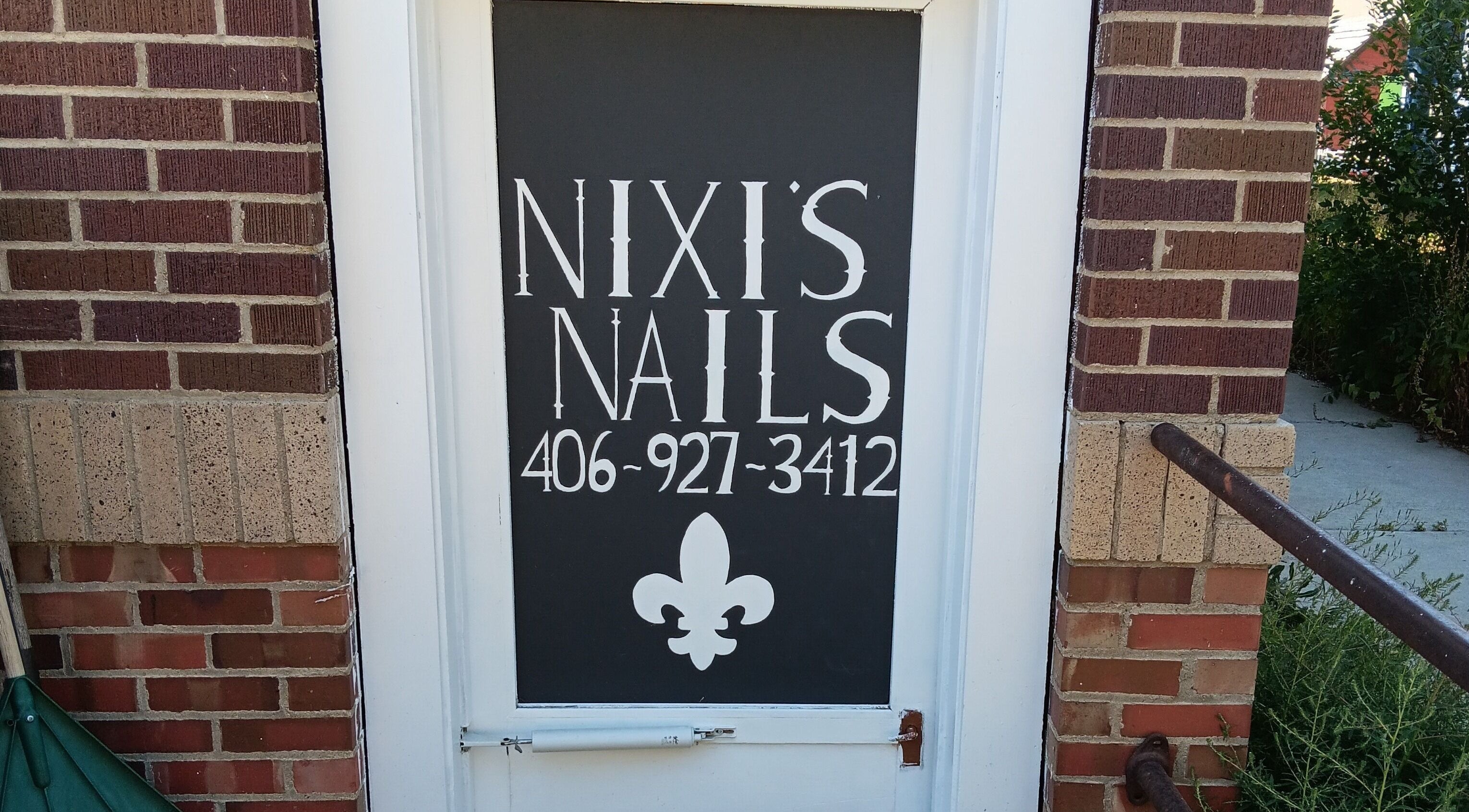 Front door of Nixi's Nails Salon in Roundup, Montana, US with stylish signage.