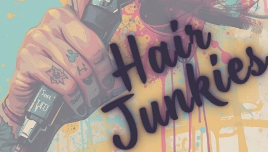 Colorful tattooed hand with clippers at Hair Junkies, Wheaton, Illinois, US, showcasing unique salon vibe.