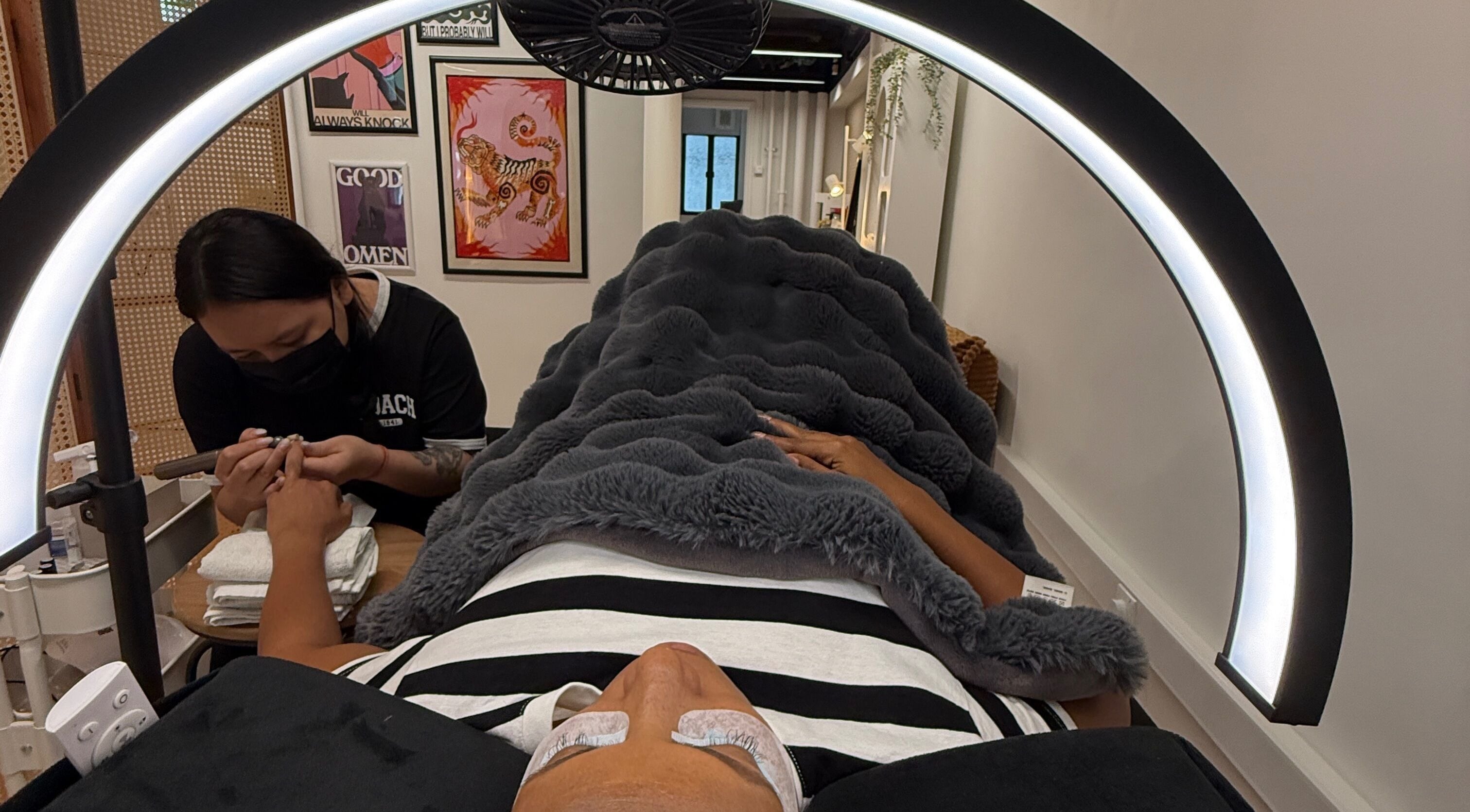 Client receives nail care at Good Omen Studio, Hong Kong Island, HK, under a cozy blanket and soft light.