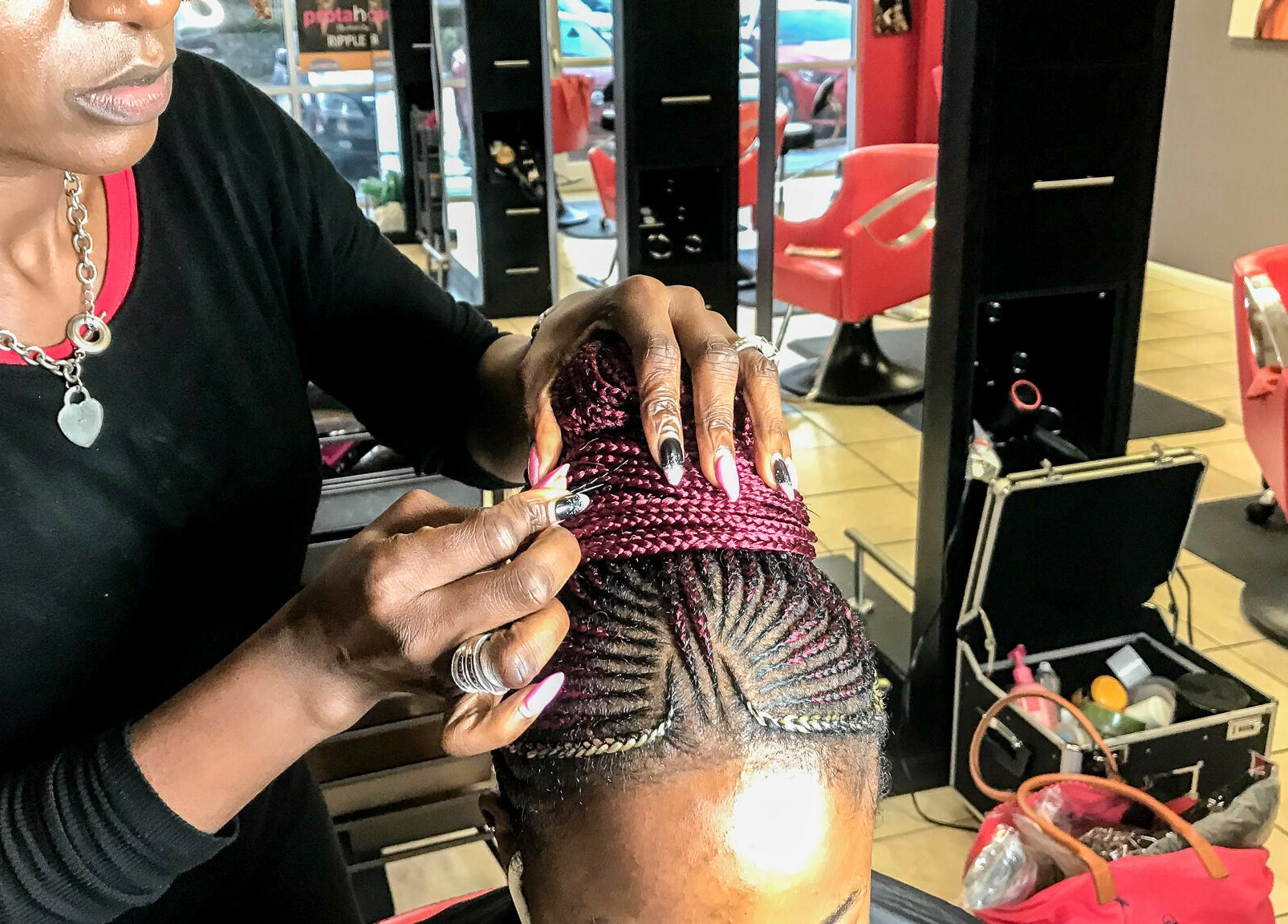 Hair stylist braiding intricate cornrows at Bignons at South Tryon, Charlotte, North Carolina, US.