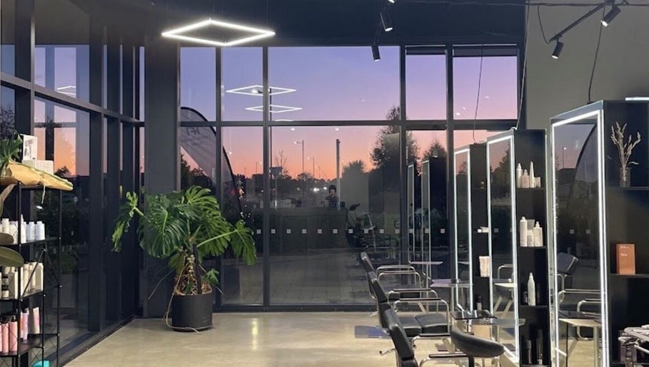 Modern salon at Urban New Concept, Christchurch, Canterbury, NZ, with sunset reflecting in glass walls.
