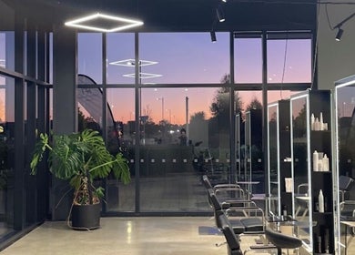 Modern salon at Urban New Concept, Christchurch, Canterbury, NZ, with sunset reflecting in glass walls.