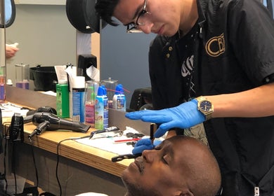 Barber skillfully shaves client at Champions Barbering Institute in Portland, Oregon, US.