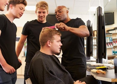 Training session at Champions Barbering Institute, Portland, Oregon, US with students learning hairstyling.