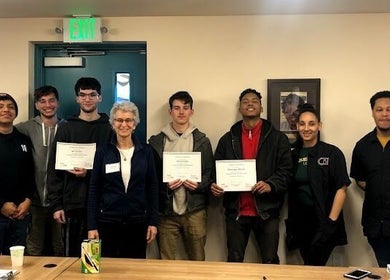 Graduates with certificates at Champions Barbering Institute, Portland, Oregon, US celebrating success.