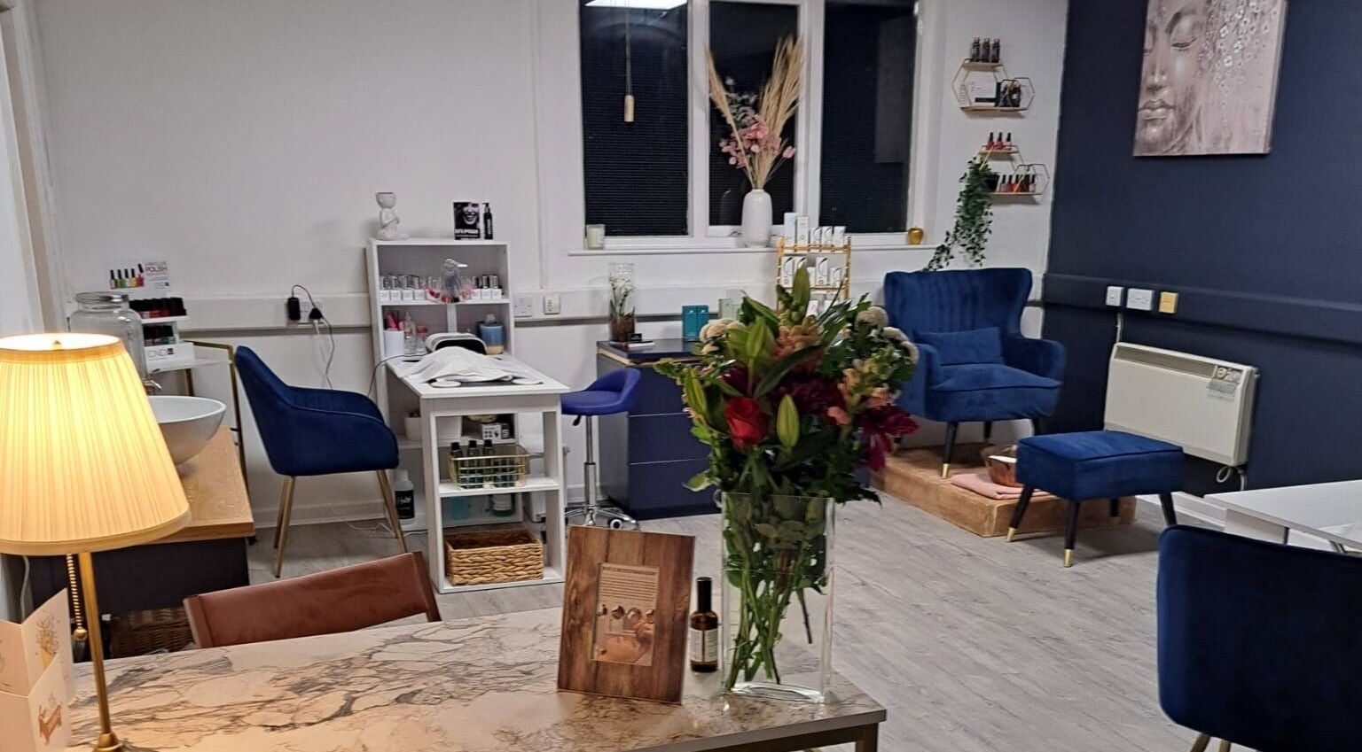 Cozy interior of Bespoke Beauty SP in Newton-Le-Willows, England, GB with plush blue chairs and floral arrangement.