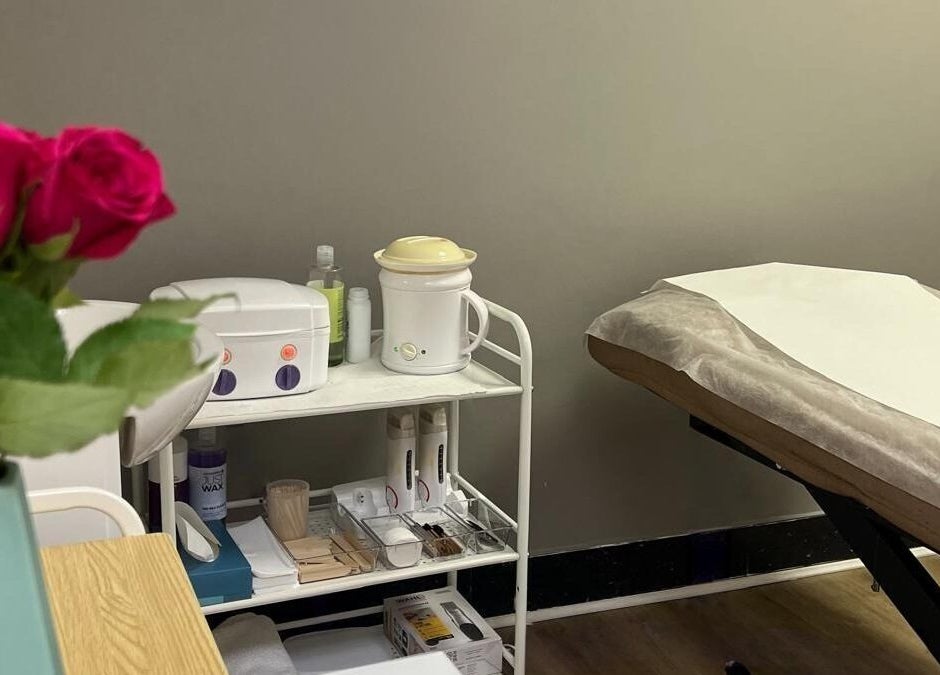 A tranquil treatment room at Skimprove, London, England, GB, featuring roses, a massage bed, and beauty equipment.