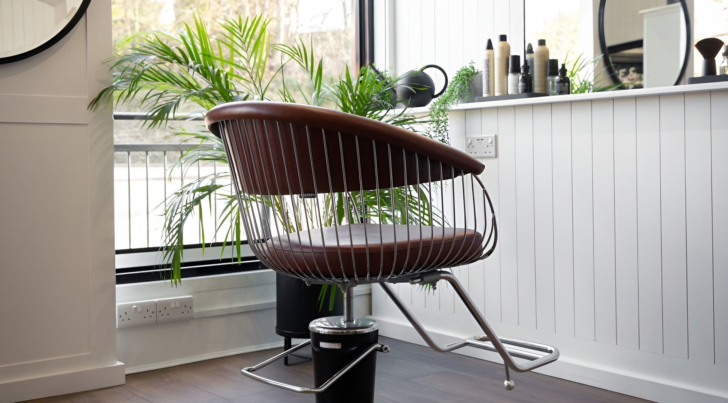 Modern styling chair at Rose and Rogue salon, Sevenoaks, England, GB, with lush plants and large mirror.