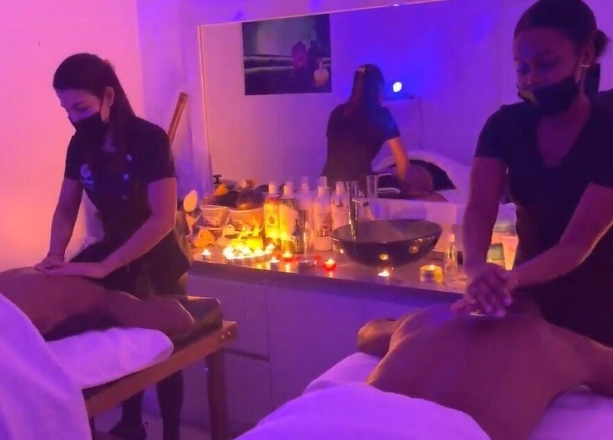 Terapistas brindan un masaje en Skin Perfect Curacao, Willemstad, CW, en un ambiente iluminado con velas.