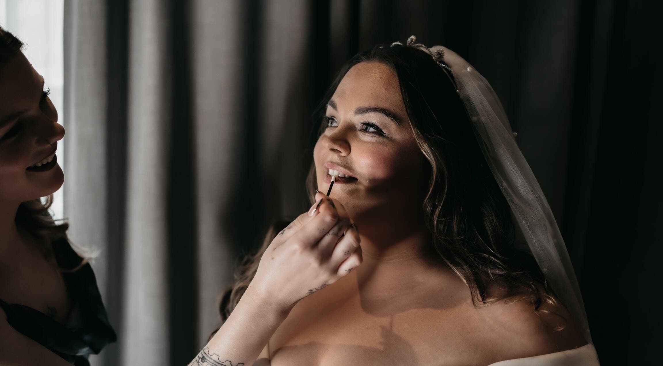 Bride having makeup applied, radiating joy by Heather Connor at Elevate, Linlithgow, Scotland, GB.