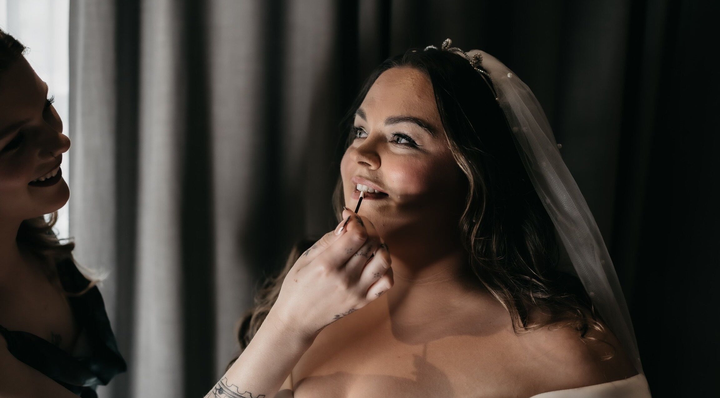 Bride having makeup applied, radiating joy by Heather Connor at Elevate, Linlithgow, Scotland, GB.