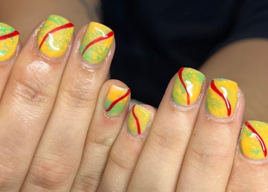 Bright yellow and green nail art with red streaks at Pops Beauty Studio, Gwent, Wales, GB.