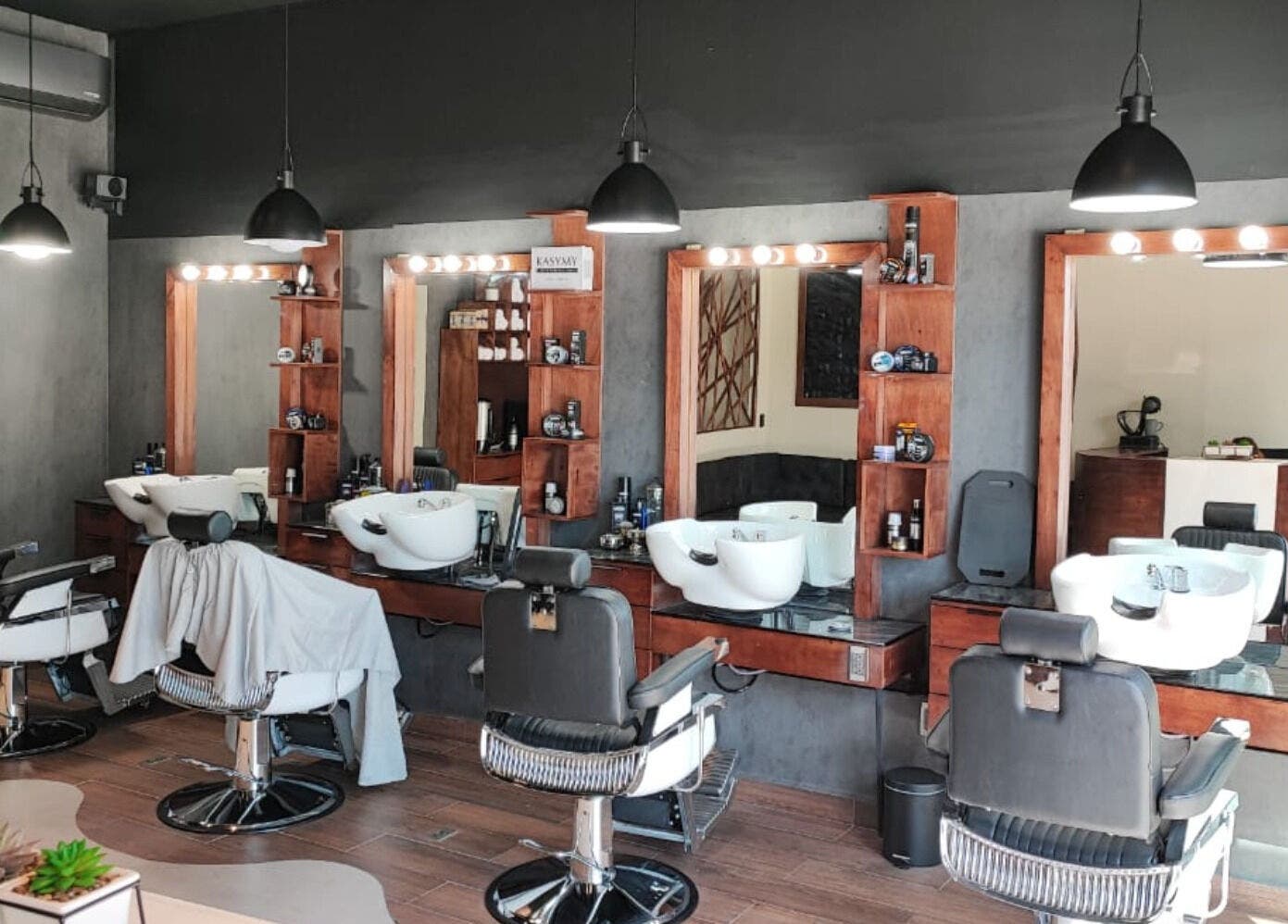 Interior de Wötzer Barbería & Spa en Juriquilla, Querétaro, MX, mostrando sillas y espejos elegantes.