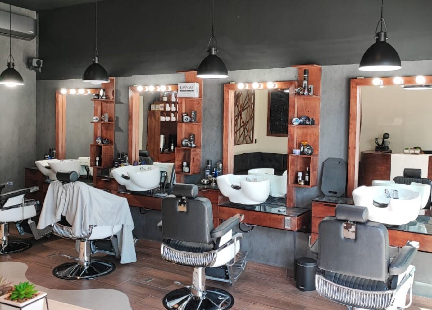 Interior de Wötzer Barbería & Spa en Juriquilla, Querétaro, MX, mostrando sillas y espejos elegantes.