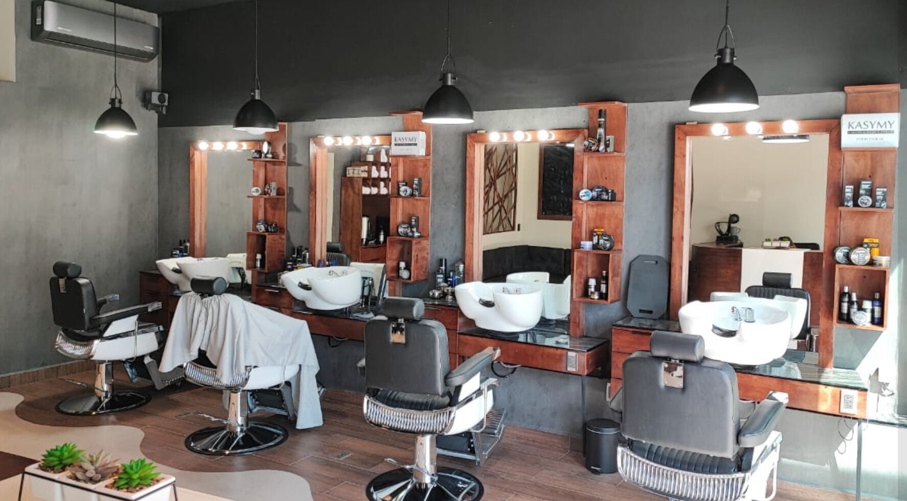 Interior de Wötzer Barbería & Spa en Juriquilla, Querétaro, MX, mostrando sillas y espejos elegantes.