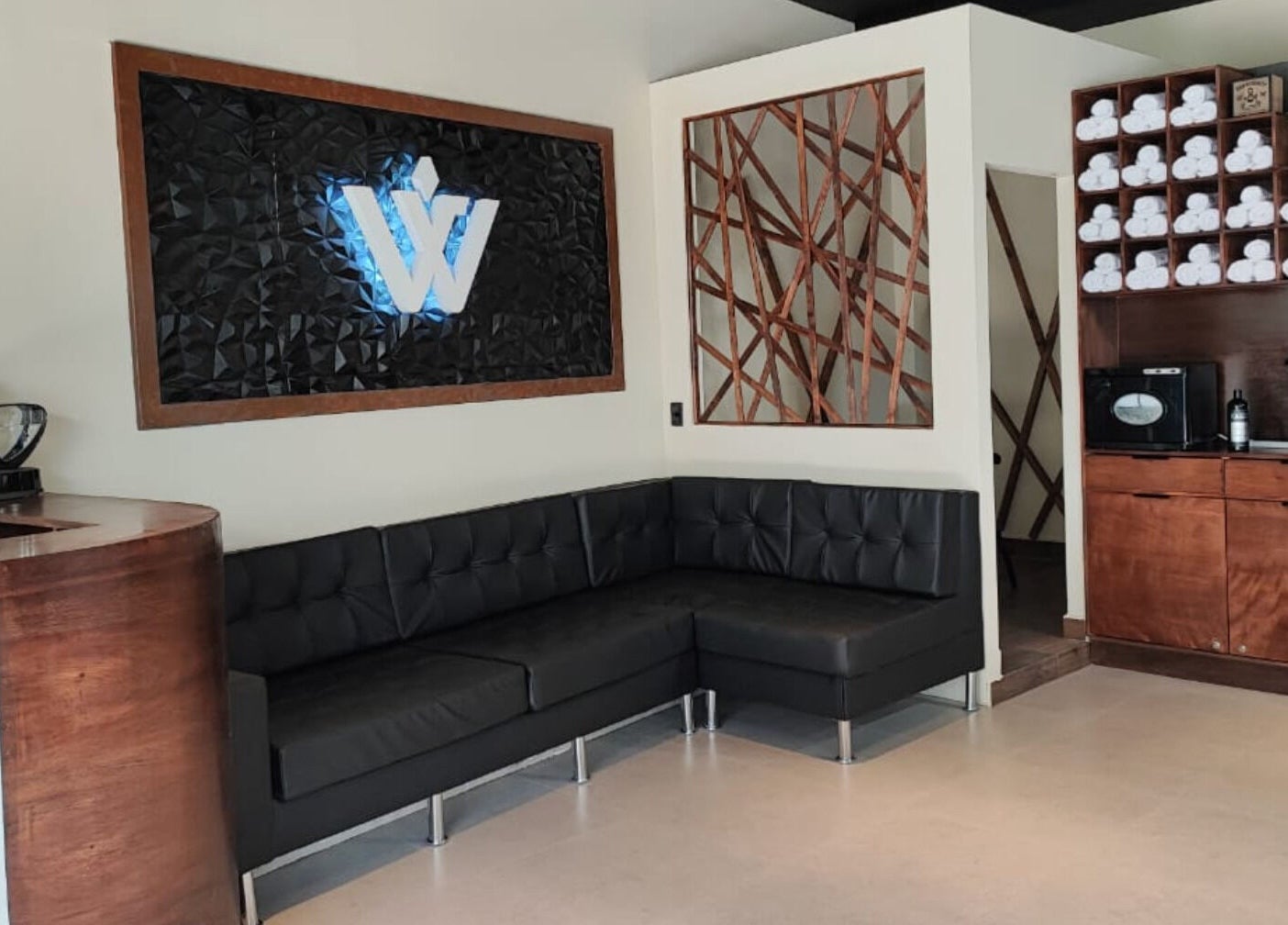 Acogedor área de espera en Wötzer Barbería & Spa, Juriquilla, Querétaro, MX con sofá negro y decoración moderna.