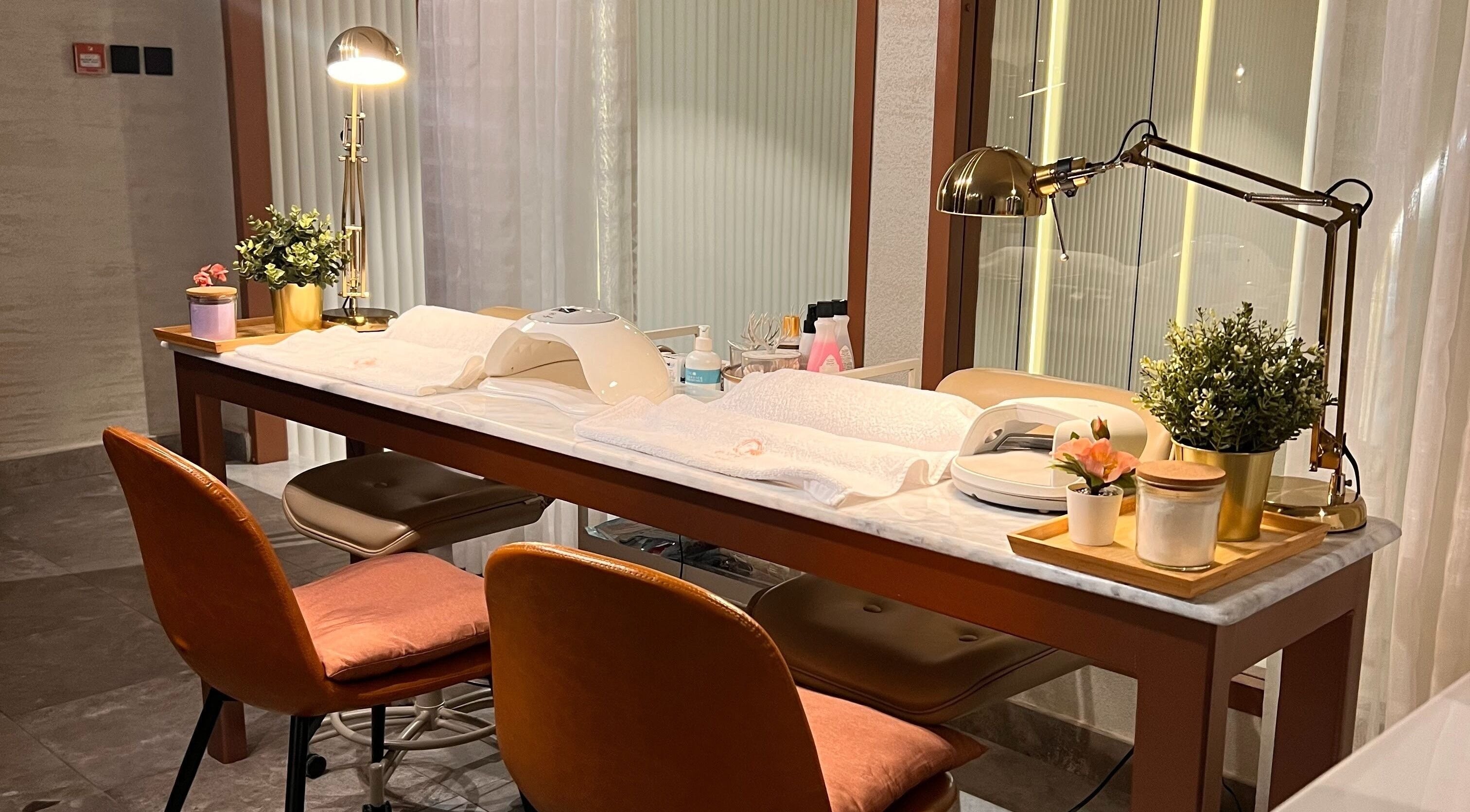 Sophisticated manicure station at Qmra Salon, Jeddah, Makkah Province, SA, with cozy chairs and ambient lighting.