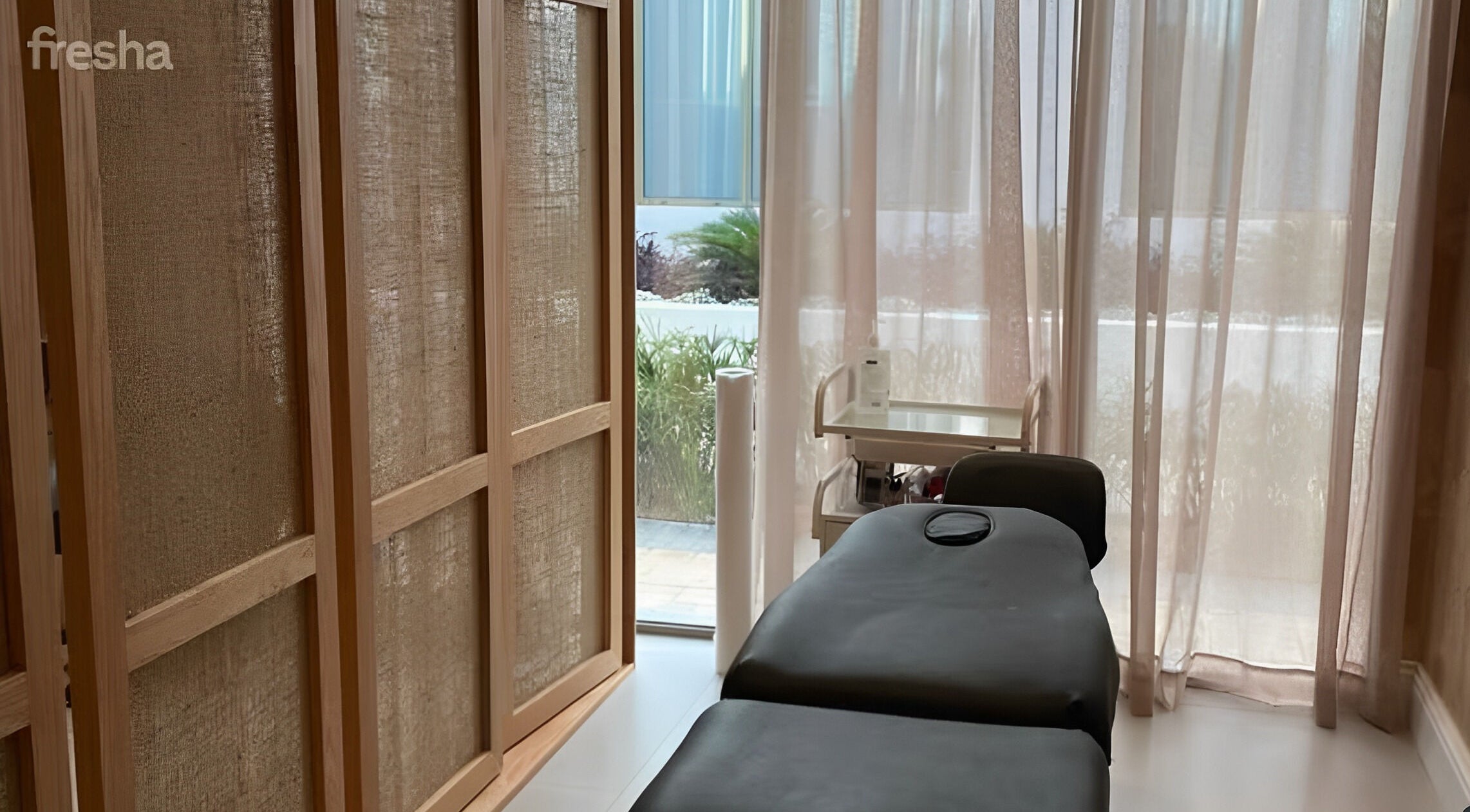 Relaxing massage room at Zoz Lashes - Dariyah, Diriyah, SA with soft light through curtains and cozy treatment bed.