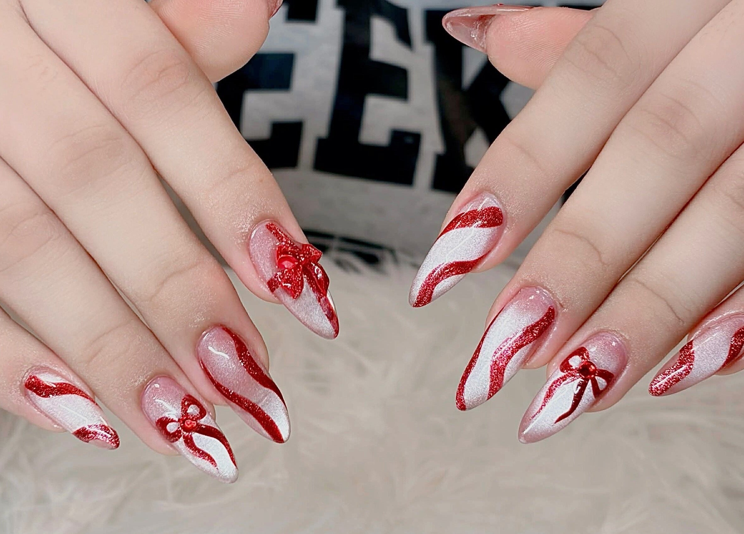 Red and white glittery nails with bows from Beauticure Nails in Toronto, Ontario, CA.
