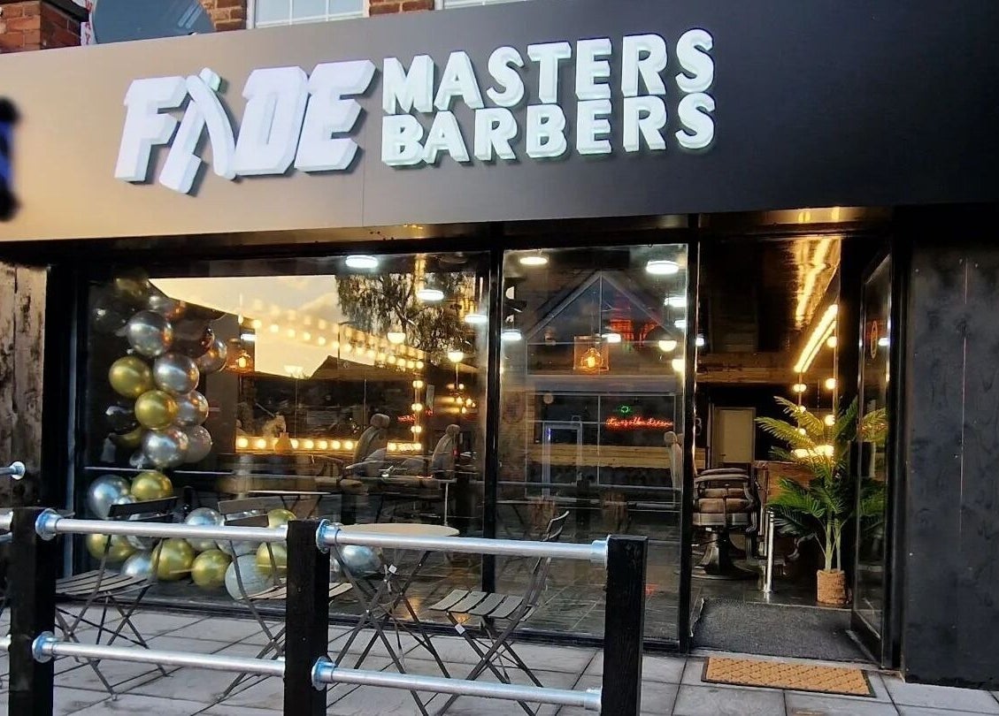 Exterior of Fade Masters Barbers & Tanning Salon Hale in Hale Barns, England, featuring stylish lighting.