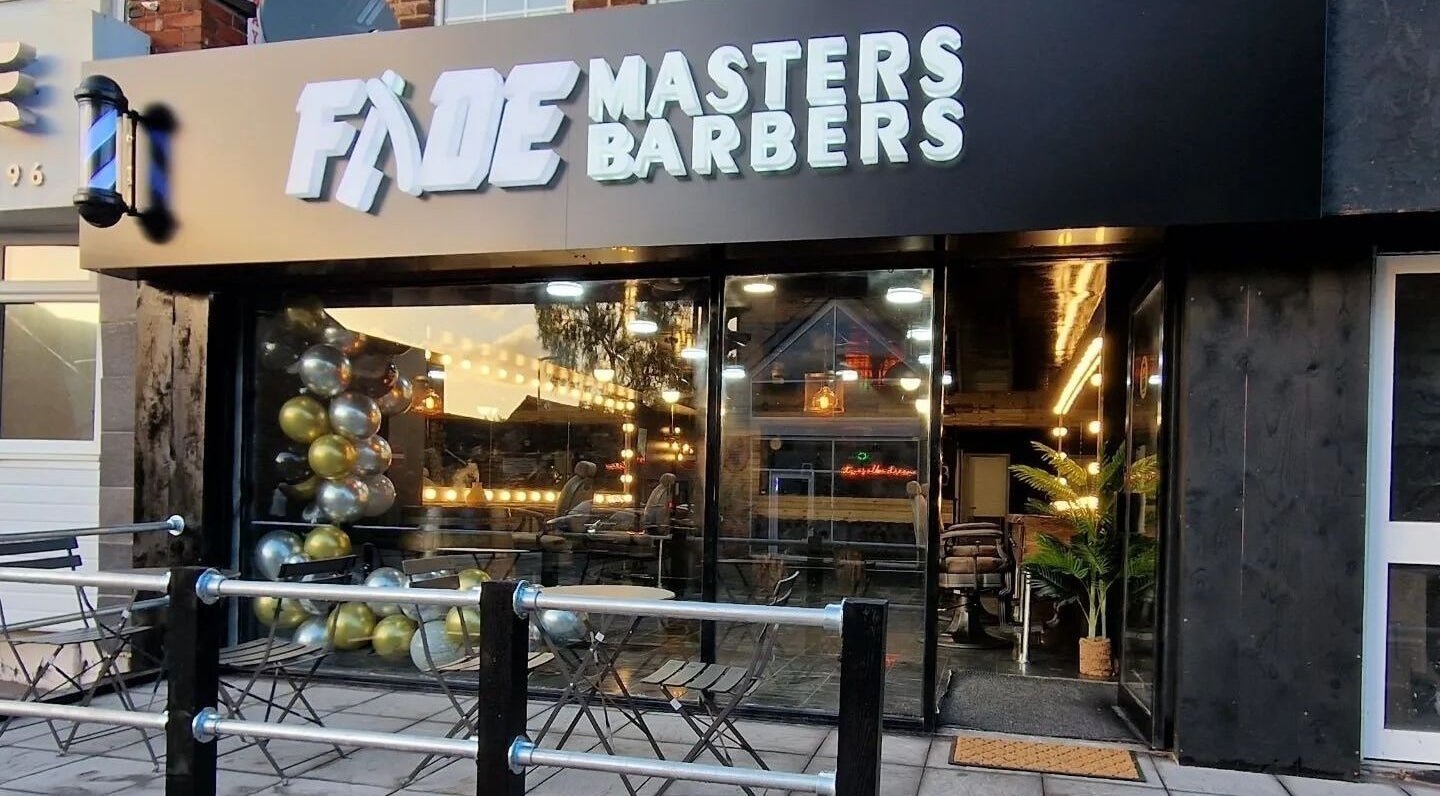 Exterior of Fade Masters Barbers & Tanning Salon Hale in Hale Barns, England, featuring stylish lighting.