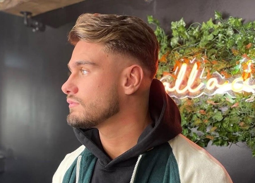 A stylish haircut at Fade Masters Barbers & Tanning Salon Hale Barns, England, GB with neon and greenery decor.