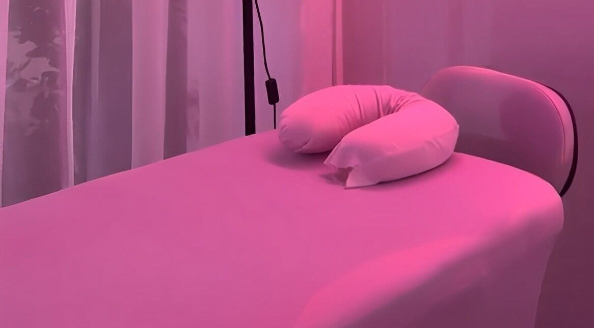 Relaxing massage bed at Lash and Dash, Sandton, Gauteng, ZA, illuminated by soothing pink light.
