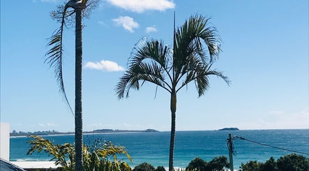 Scenic beach view from The Sanctuary, Kingscliff, New South Wales, AU with clear sky and palm trees.