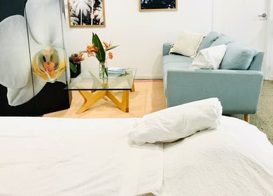 Relaxing lounge at The Sanctuary, Kingscliff, New South Wales, AU with sofa, glass table, and floral decor.