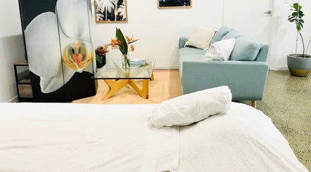 Relaxing lounge at The Sanctuary, Kingscliff, New South Wales, AU with sofa, glass table, and floral decor.