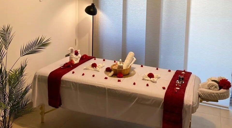 Elegant massage setup at Revives Home Spa in Dubai, Dubai, AE with red accents and rolled towels.