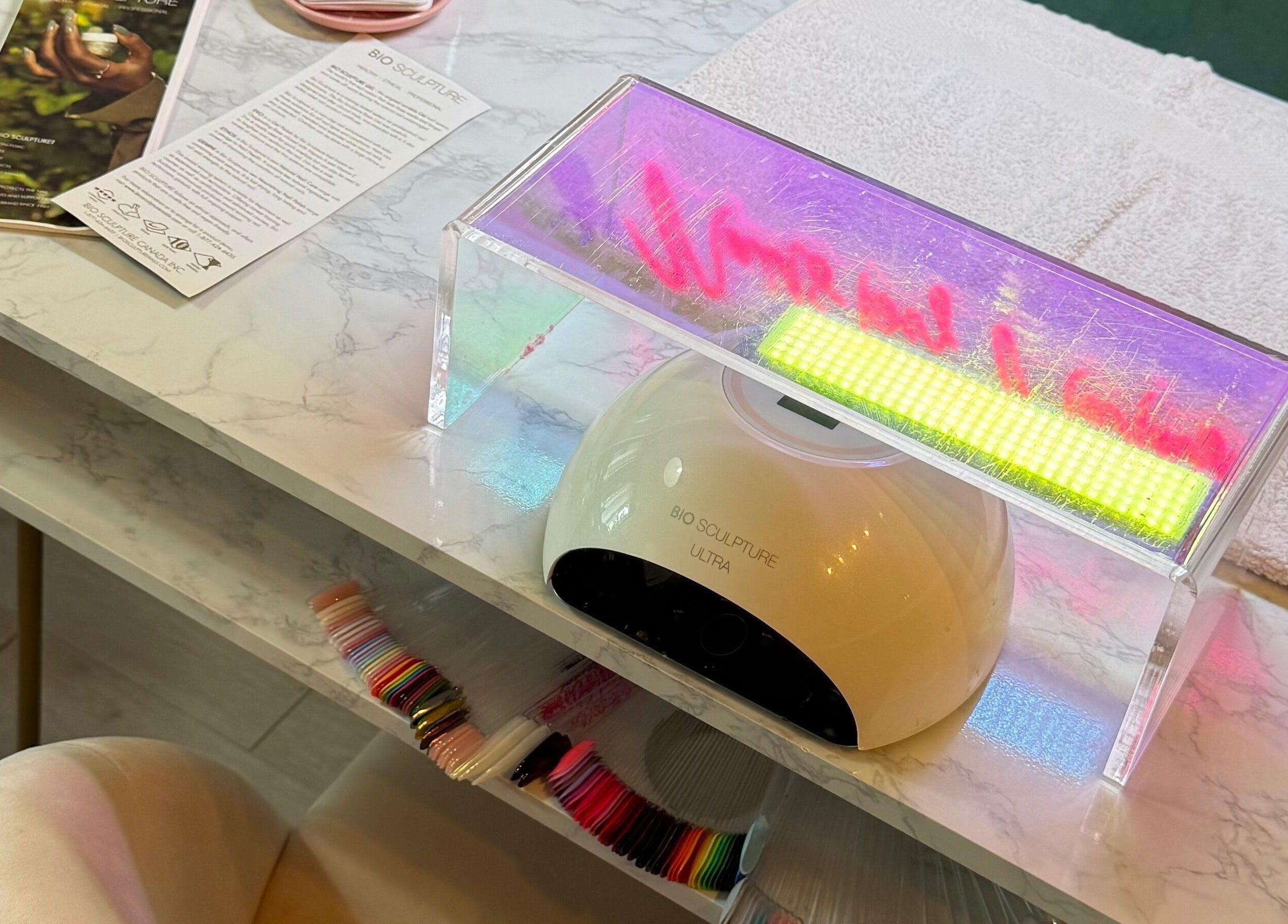 Nail station at Nails By Natasha in Dorval, Quebec, CA, featuring a UV lamp and colorful nail polish samples.
