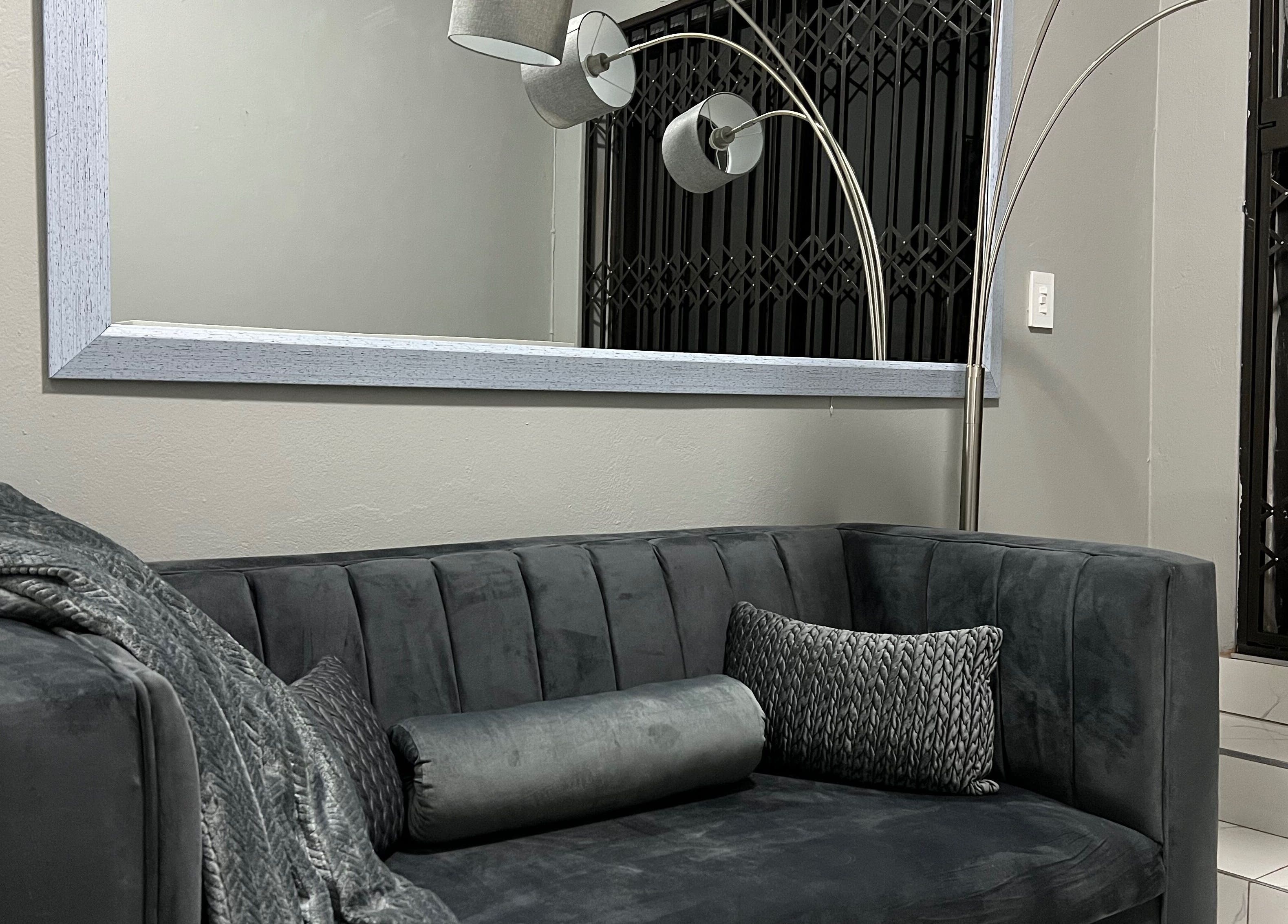 Cozy lounge area at Ash Ed Beauty Suite in Germiston, Gauteng, ZA, with a plush gray sofa and modern lighting.