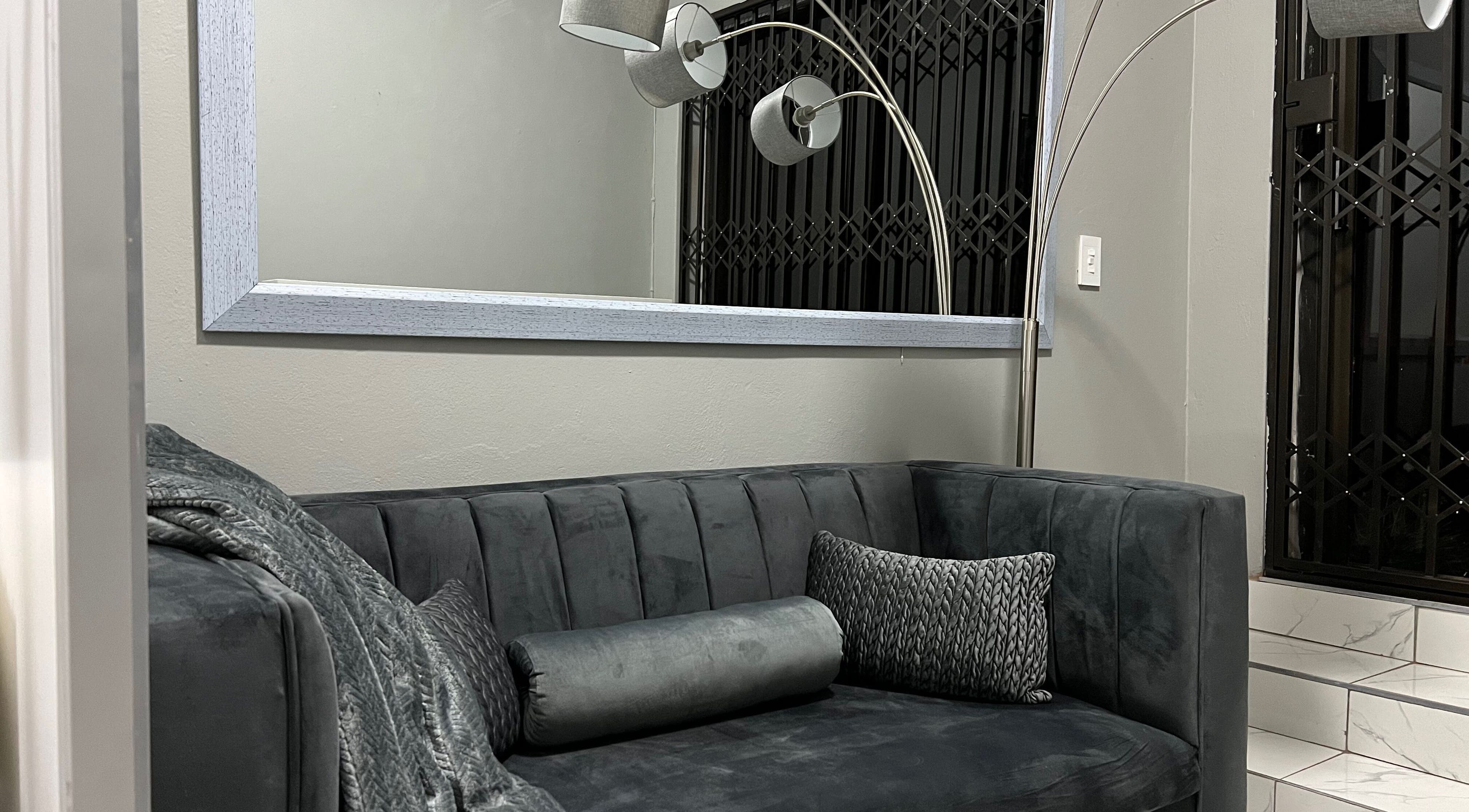 Cozy lounge area at Ash Ed Beauty Suite in Germiston, Gauteng, ZA, with a plush gray sofa and modern lighting.