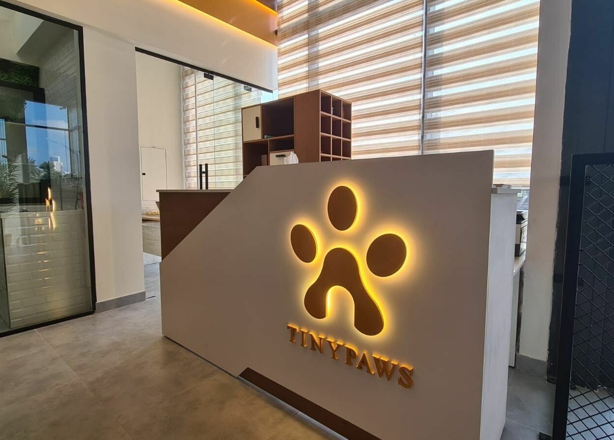 Reception area of Tiny Paws, Dubai, AE featuring an illuminated paw logo and modern decor.