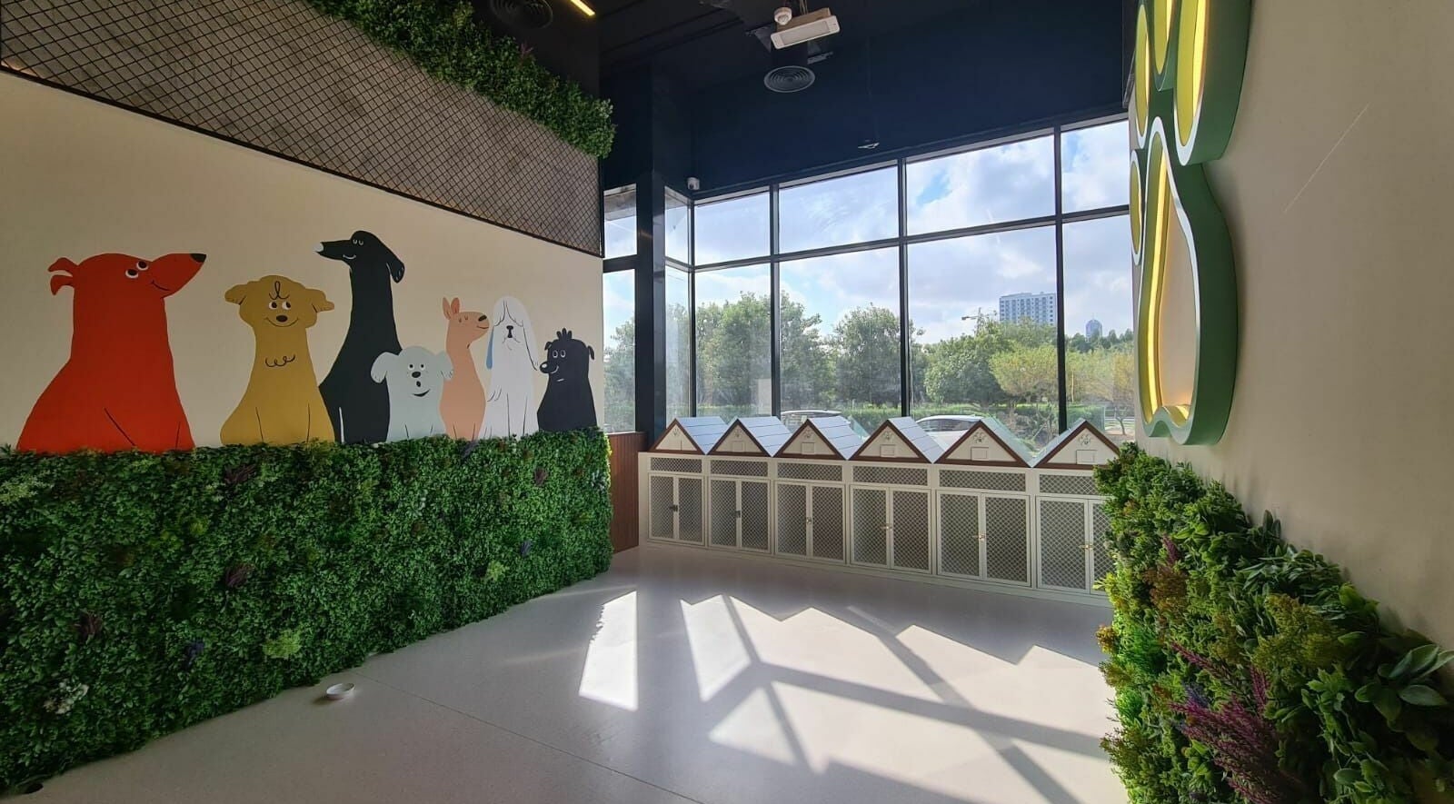 Bright interior of Tiny Paws in Dubai, AE. Colorful dog mural and cozy kennels with lush greenery.