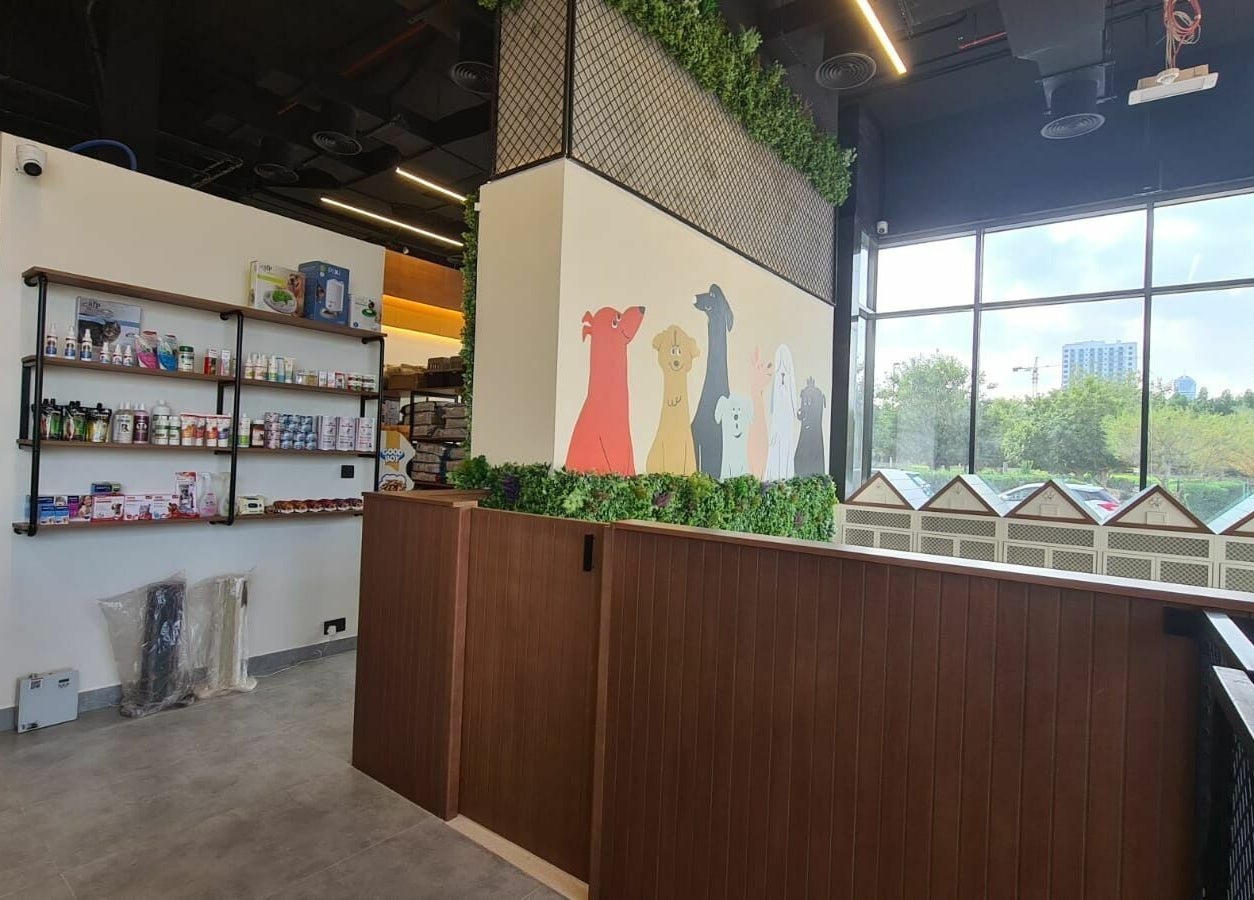 Modern pet supply wall inside Tiny Paws venue in Dubai, AE, featuring vibrant dog illustrations and greenery.