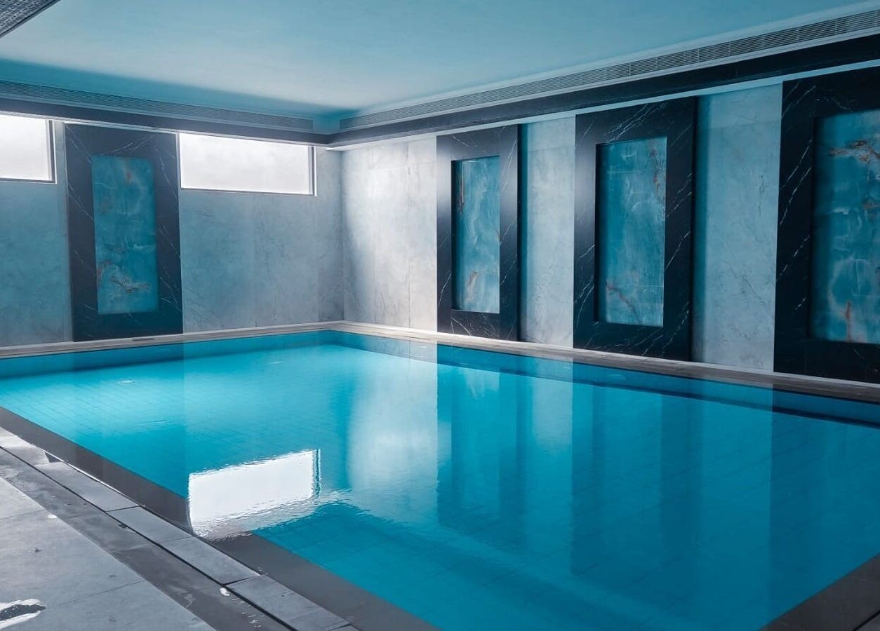 Indoor pool at Healing Zone Spa, Sharjah, AE featuring elegant blue-tiled design and ambient natural lighting.