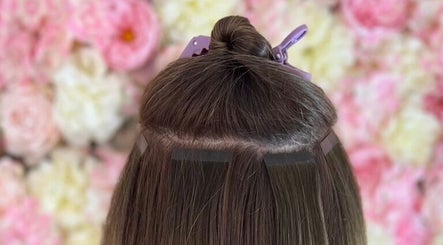Hair extensions application at Popellas Hair & Extensions, Bournemouth, England, GB. Pink flower backdrop.
