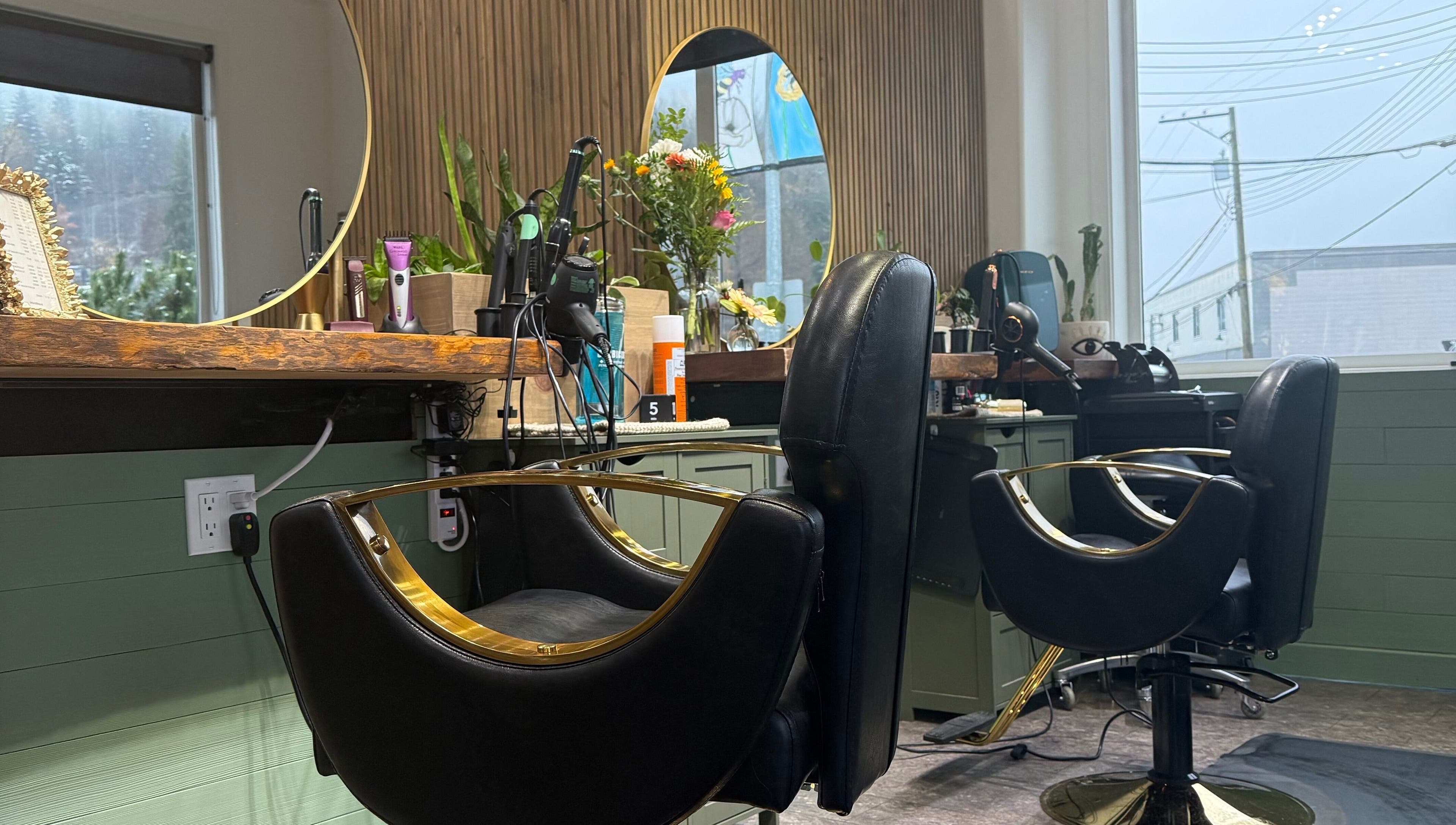 Elegant salon stations at The Collective Beauty Company, Revelstoke, BC, CA with black chairs and mirrors.